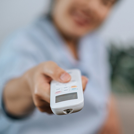 Mujer con control remoto universal en la mano